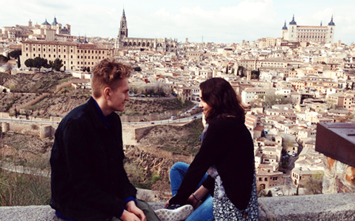 Two people sitting on a wall overlooking a city
