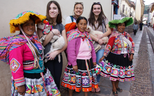 Students holding lambs with Peruvian locals