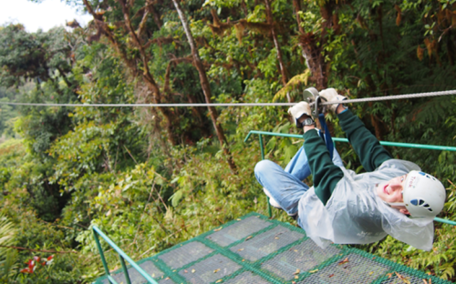 Guy ziplining in jungle