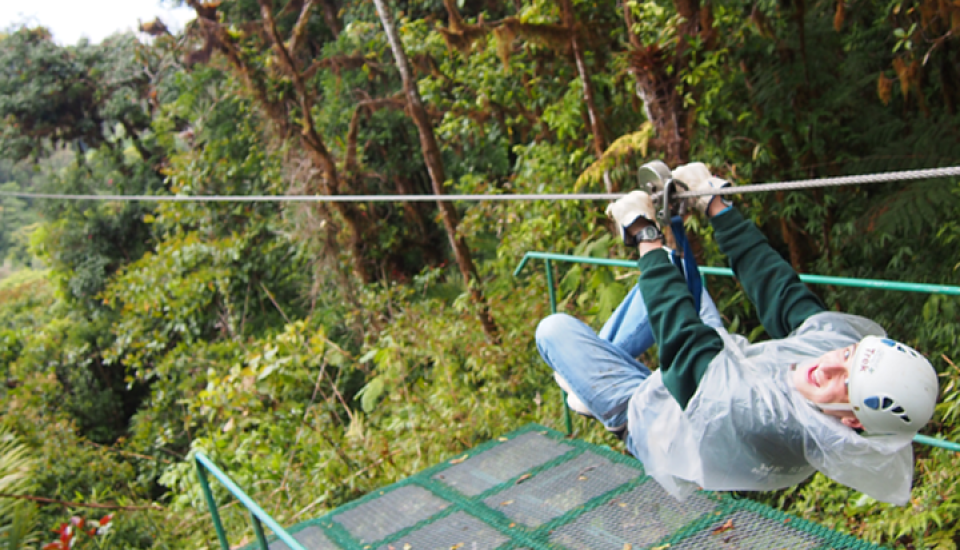 Guy ziplining in jungle