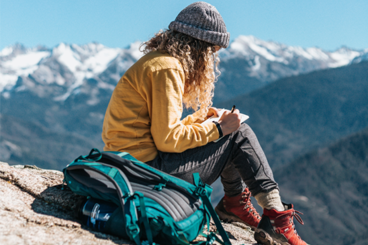 Girl journaling on a mountain