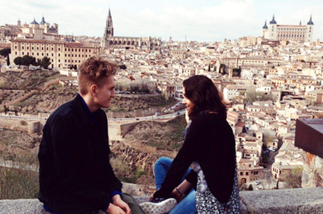 Two people sitting on a wall overlooking a city