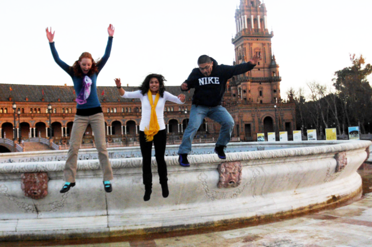 3 people jumping off a fountain ledge