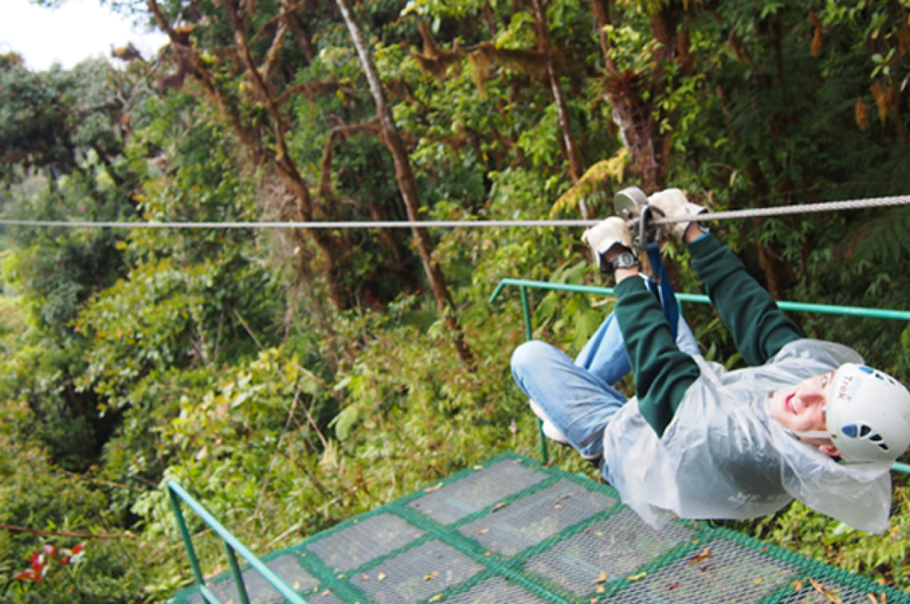 Guy ziplining in jungle